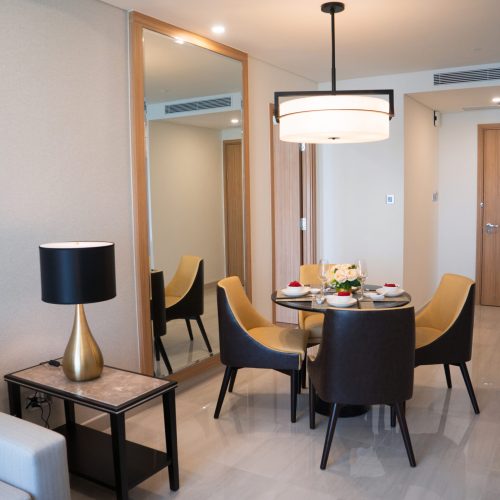 Dining area of comfortable studio flat or hotel room. Set dining table prepared for dinner with Asian cuisine. City apartment and interior concept